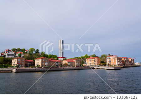 Colony of small wooden historic houses on the Slottsberget mountain with the tallest Scandinavian building Karlatornet skycraper in Lindholmen in background, Gothenburg, Sweden 133067122