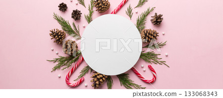 Flat lay Christmas composition. Round Paper blank, pine tree branches, christmas decorations on Colored background. Top view, copy space for text Flat lay Christmas composition. Round Paper blank, pine tree branches, christmas decorations on Colored background. Top view, copy space for text 133068343