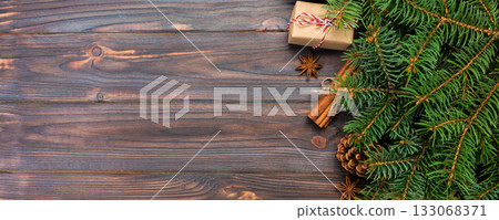Christmas background with fir tree and gift box on wooden table. Top view with copy space for your design Christmas background with fir tree and gift box on wooden table. Top view with copy space for your design 133068371