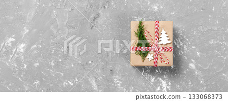 gift box wrapped in recycled paper, with ribbon bow, with christmas decor. Cement table background, copy space gift box wrapped in recycled paper, with ribbon bow, with christmas decor. Cement table background, copy space 133068373