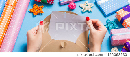 Top view of woman holding an envelope on blue background made of holiday decorations. Christmas time concept Top view of woman holding an envelope on blue background made of holiday decorations. Christmas time concept 133068380