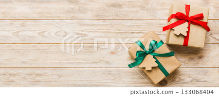 wrapped christmas or other holiday handmade present in paper with colored ribbon. Present box, decoration of gift on colourfull table, top view with copy space wrapped christmas or other holiday handmade present in paper with colored ribbon. Present box, decoration of gift on colourfull table, top view with copy space 133068404