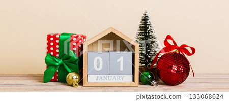 25 december. Christmas composition on colored background with a wooden calendar, with a gift box, toys, bauble copy space 25 december. Christmas composition on colored background with a wooden calendar, with a gift box, toys, bauble copy space 133068624