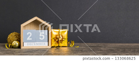 25 december. Christmas composition on colored background with a wooden calendar, with a gift box, toys, bauble copy space 133068625