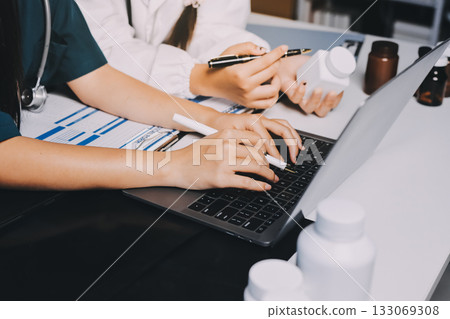 Group of doctors attending seminar in hospital lecture hall with senior physician giving medical presentation and professional training session on healthcare practices Group of doctors attending seminar in hospital lecture hall with senior physician giving medical presentation and professional training session on healthcare practices 133069308