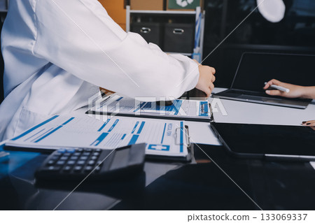 Group of doctors attending seminar in hospital lecture hall with senior physician giving medical presentation and professional training session on healthcare practices Group of doctors attending seminar in hospital lecture hall with senior physician giving medical presentation and professional training session on healthcare practices 133069337