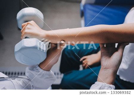 old woman training with physiotherapist using dumbbells at home therapist assisting senior woman with exercises in nursing home elderly patient using dumbbells with outstretched arms no logos no bran old woman training with physiotherapist using dumbbells at home therapist assisting senior woman with exercises in nursing home elderly patient using dumbbells with outstretched arms no logos no bran 133069382