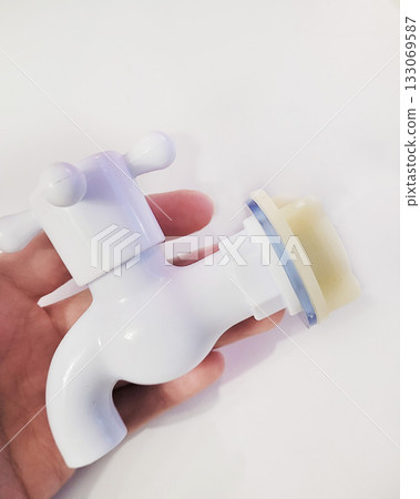 White Plastic Faucet Held in Human Hand 133069587