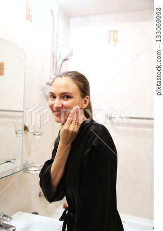 Woman Cleansing Face, Smiling In Bathroom Woman Cleansing Face, Smiling In Bathroom 133069998