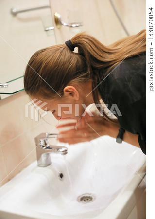 Woman Washing Face In Bathroom Sink 133070054