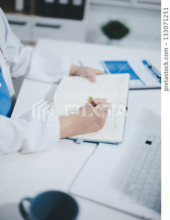 Middle aged female doctor working on laptop in doctor's room Middle aged female doctor working on laptop in doctor's room 133071251