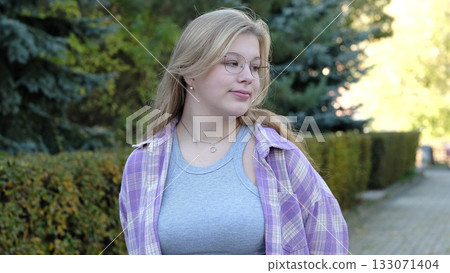 A young woman with glasses and a plaid shirt gazes thoughtfully into the distance in a serene outdoor setting. This photo captures calmness and the quiet beauty of contemplation. A young woman with glasses and a plaid shirt gazes thoughtfully into the distance in a serene outdoor setting. This photo captures calmness and the quiet beauty of contemplation. 133071404