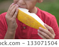 he texture of the melon is vivid as a young boy savors it, his enjoyment evident in his expression. Emphasizes the delight of simple, wholesome eating. 133071504