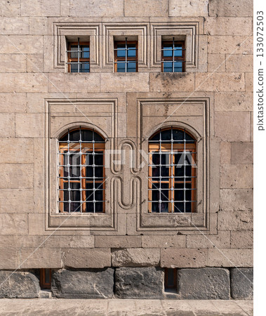 Historic stone facade with ornate carvings and barred windows 133072503