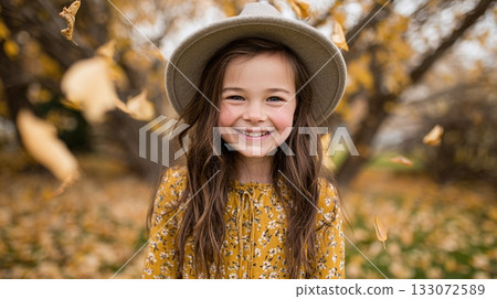 A girl with long brown hair and a tan hat smiles brightly in a field with autumn leaves falling around her, creating a warm and cheerful scene. She is wearing a dress with a pattern. A girl with long brown hair and a tan hat smiles brightly in a field with autumn leaves falling around her, creating a warm and cheerful scene. She is wearing a dress with a pattern. 133072589