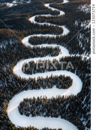 Drone aerial of winding groomed ski run cutting through dark evergreen forest high mountain winter resort Drone aerial of winding groomed ski run cutting through dark evergreen forest high mountain winter resort 133073754