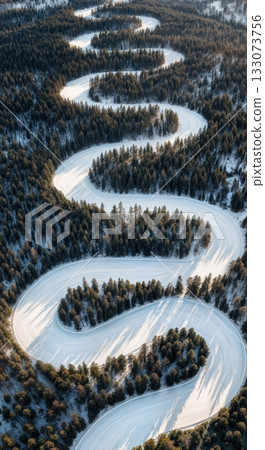 Drone aerial of winding groomed ski run cutting through dark evergreen forest high mountain winter resort Drone aerial of winding groomed ski run cutting through dark evergreen forest high mountain winter resort 133073756