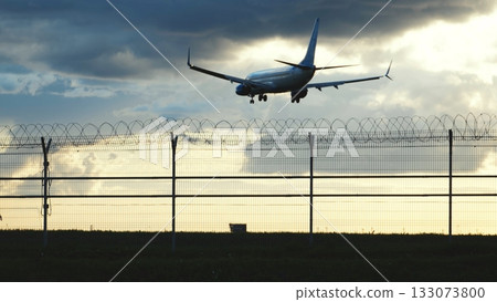 Airplane landing at airport with security fence at sunset, travel concept Airplane landing at airport with security fence at sunset, travel concept 133073800