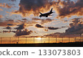 Passenger airplane landing at sunset over airport fence 133073803
