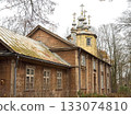 Abandoned wooden orthodox church with peeling paint, gilded cupolas and weathered crosses, overgrown yard and bare autumn trees. 133074810