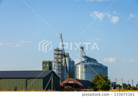 Granary construction is underway with silos being built alongside agricultural warehouses under a clear blue sky Granary construction is underway with silos being built alongside agricultural warehouses under a clear blue sky 133075161