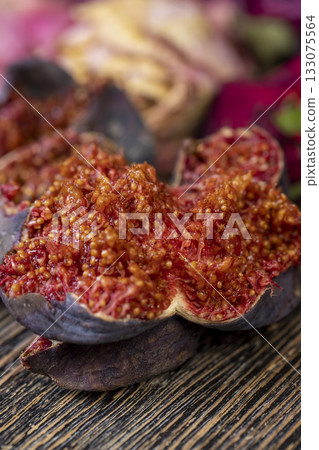moldy whole overripe and spoiled figs with red flesh and seeds on a table, moldy spoiled figs with lots of grains 133075564