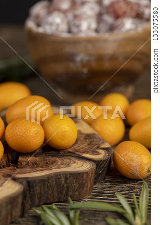 fresh and dried kumquat fruits on the table, fresh orange kumquats and dehydrated dried kumquats sprinkled with powdered sugar, close up fresh and dried kumquat fruits on the table, fresh orange kumquats and dehydrated dried kumquats sprinkled with powdered sugar, close up 133075580