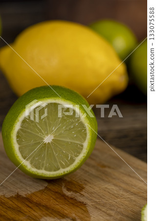 sliced juicy green lime lying on the table with yellow lemons , sliced ripe citrus fruits lime and large lemons are lying on a wooden table sliced juicy green lime lying on the table with yellow lemons , sliced ripe citrus fruits lime and large lemons are lying on a wooden table 133075588