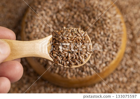 flax seeds poured into a wooden bowl, a round wooden bowl completely filled with flax seeds, which can be used both for nutrition and for obtaining a crop 133075597