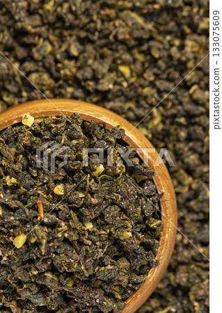 aromatic tea with the addition of dried ripe peach fruits in a wooden bowl , dried high-quality leaf tea poured into a bowl with natural flavors and a piece of ripe natural fruits aromatic tea with the addition of dried ripe peach fruits in a wooden bowl , dried high-quality leaf tea poured into a bowl with natural flavors and a piece of ripe natural fruits 133075609