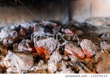 Glowing red embers and hot charcoal briquettes producing intense heat, ready for cooking food 133076110