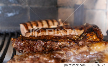 Juicy argentine barbecue meat grilling on a charcoal parrillada, preparing delicious cuts of beef and chorizo for a traditional outdoor meal, fresh food cooking Juicy argentine barbecue meat grilling on a charcoal parrillada, preparing delicious cuts of beef and chorizo for a traditional outdoor meal, fresh food cooking 133076124