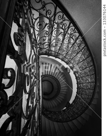 Spiral staircase with ornate iron railing in black and white architectural interior shot 133076144
