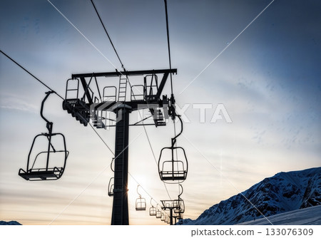 Ski lift towers and cables silhouetted against dramatic winter sky low angle industrial alpine infrastructure Ski lift towers and cables silhouetted against dramatic winter sky low angle industrial alpine infrastructure 133076309