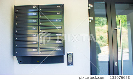 System of metal mailboxes with locks near the entrance of a residential apartment building. Urban housing detail in daylight. System of metal mailboxes with locks near the entrance of a residential apartment building. Urban housing detail in daylight. 133076628