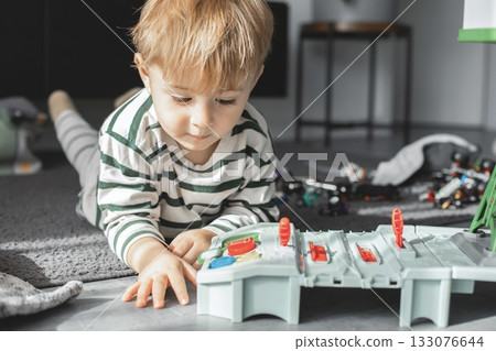 The child is focused on imaginative play, developing creativity and motor skills. Bright natural light and cozy atmosphere make this image perfect for illustrating childhood, learning through play 133076644