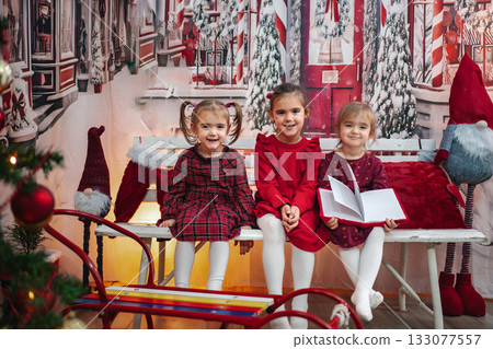 Girls celebrating Christmas on bench with festive decorations 133077557