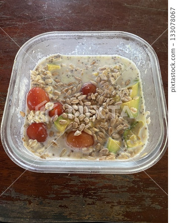 Close up view of delicious food, oatmeal porridge with fresh fruits and vegetables in a glass container, healthy food take away in boxes, diet concept Close up view of delicious food, oatmeal porridge with fresh fruits and vegetables in a glass container, healthy food take away in boxes, diet concept 133078067