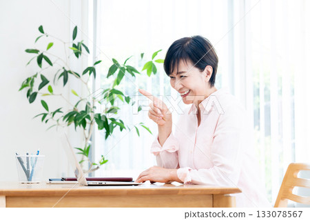 Middle-aged woman teleworking in the living room Middle-aged woman teleworking in the living room 133078567