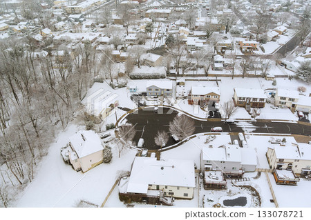 Snow blankets residential neighborhood in winter, quiet streets houses surrounded by trees 133078721