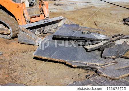 Construction equipment removing asphalt layers in busy worksite 133078725