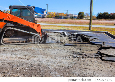 Construction equipment removes old pavement in parking lot in quiet community Construction equipment removes old pavement in parking lot in quiet community 133078729