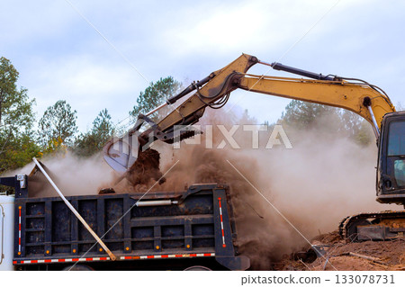 Excavator loading dirt into truck at construction site 133078731