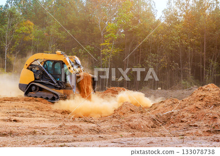 Heavy machinery clears land for construction in forested area 133078738