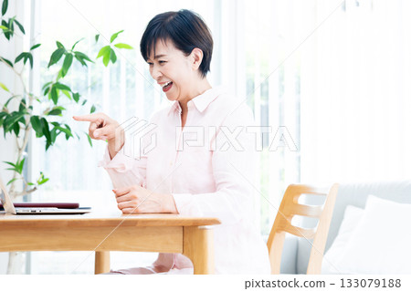 Middle-aged woman teleworking in the living room Middle-aged woman teleworking in the living room 133079188