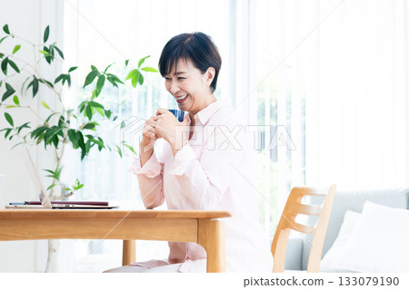 Middle-aged woman teleworking in the living room Middle-aged woman teleworking in the living room 133079190