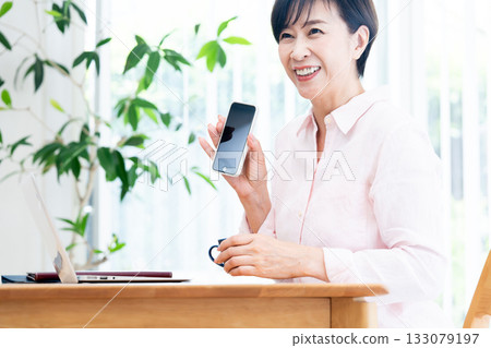Middle-aged woman teleworking in the living room Middle-aged woman teleworking in the living room 133079197