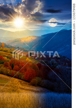 mountain landscape of countryside on autumn equinox. day and night time change concept. beautiful view of range with dappled light on forested slopes in colorful foliage with sun and moon at twilight 133079488