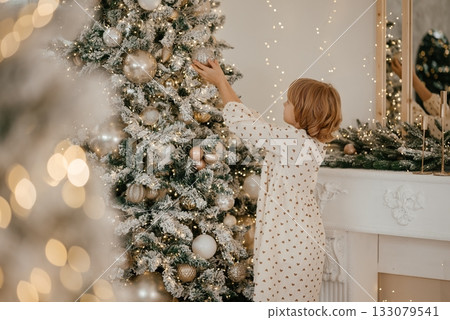 Child Decorating Christmas Tree with Joy and Wonder 133079541