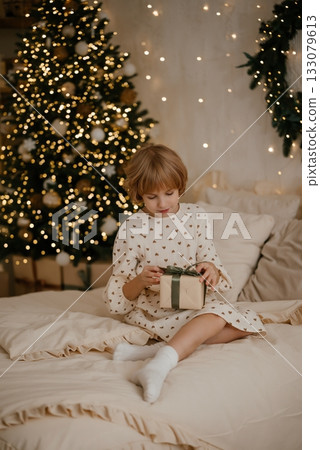 Child Opening Gift by a Christmas Tree 133079613